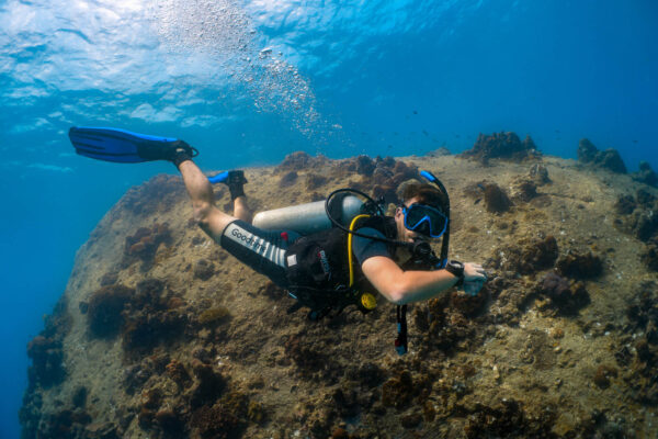 Scuba diver exploring underwater coral reef with blue fins and goggles.