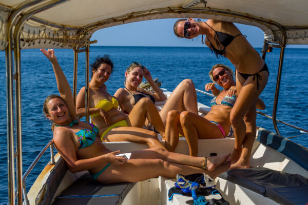 Friends enjoying a sunny day on a private boat charter snorkel tour, wearing bikinis, with the ocean in the background. Koh Tao Adventure Blog | Diving, Climbing, Snorkeling