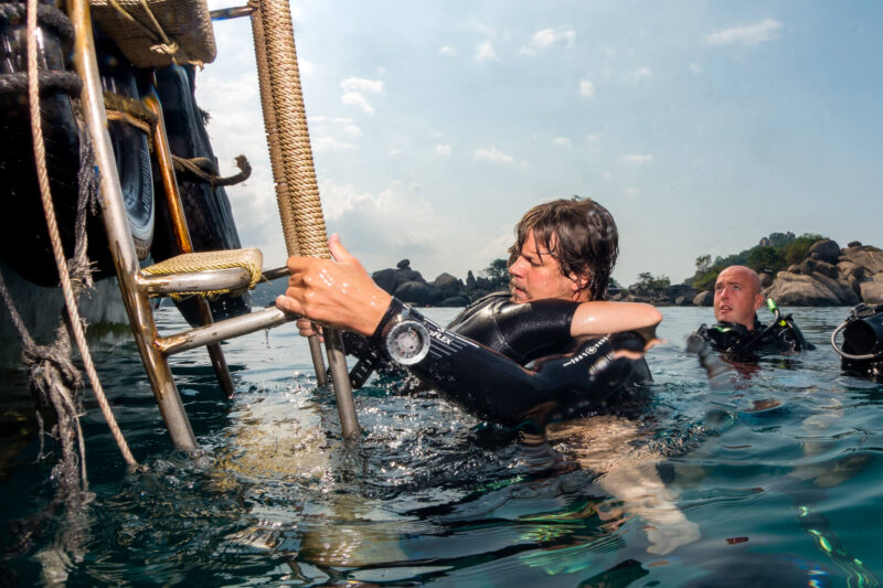 a man in a wet suit holding a ladder in the water